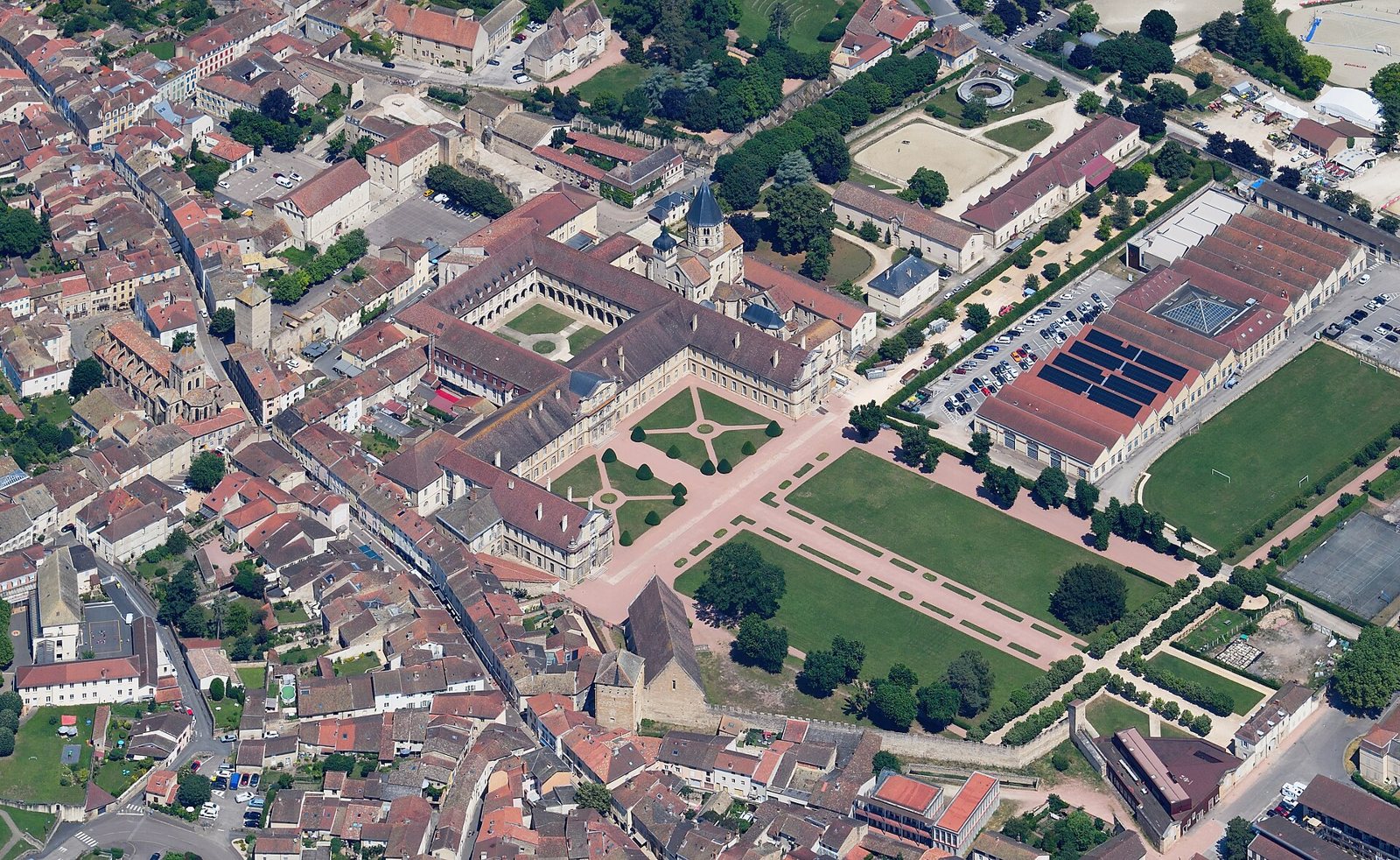 Aerial view of the town of Cluny in Burgundy, with the former abbey's cloister, gardens, long monastery buildings and lawns among red-roofed houses
