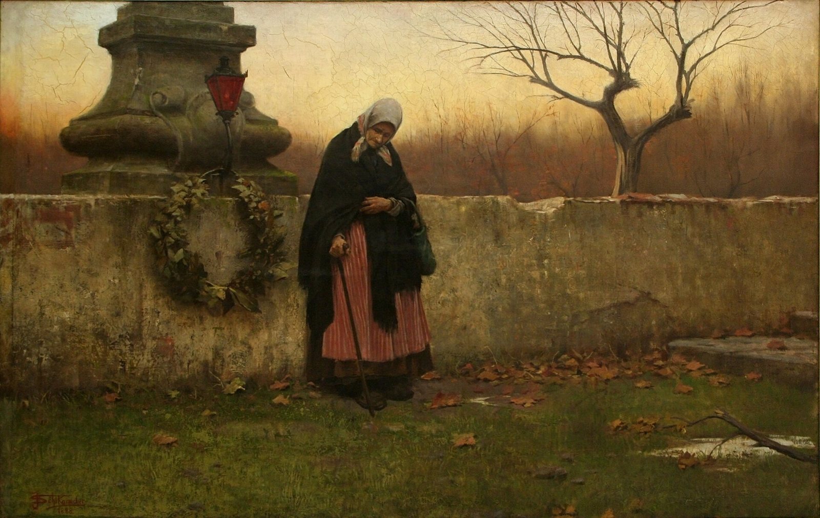 Jakub Schikaneder's All Souls' Day: an elderly woman in a dark shawl stands with bowed head beside a cemetery wall, a wreath hung below a stone cross, with leafless trees and an autumn field behind her