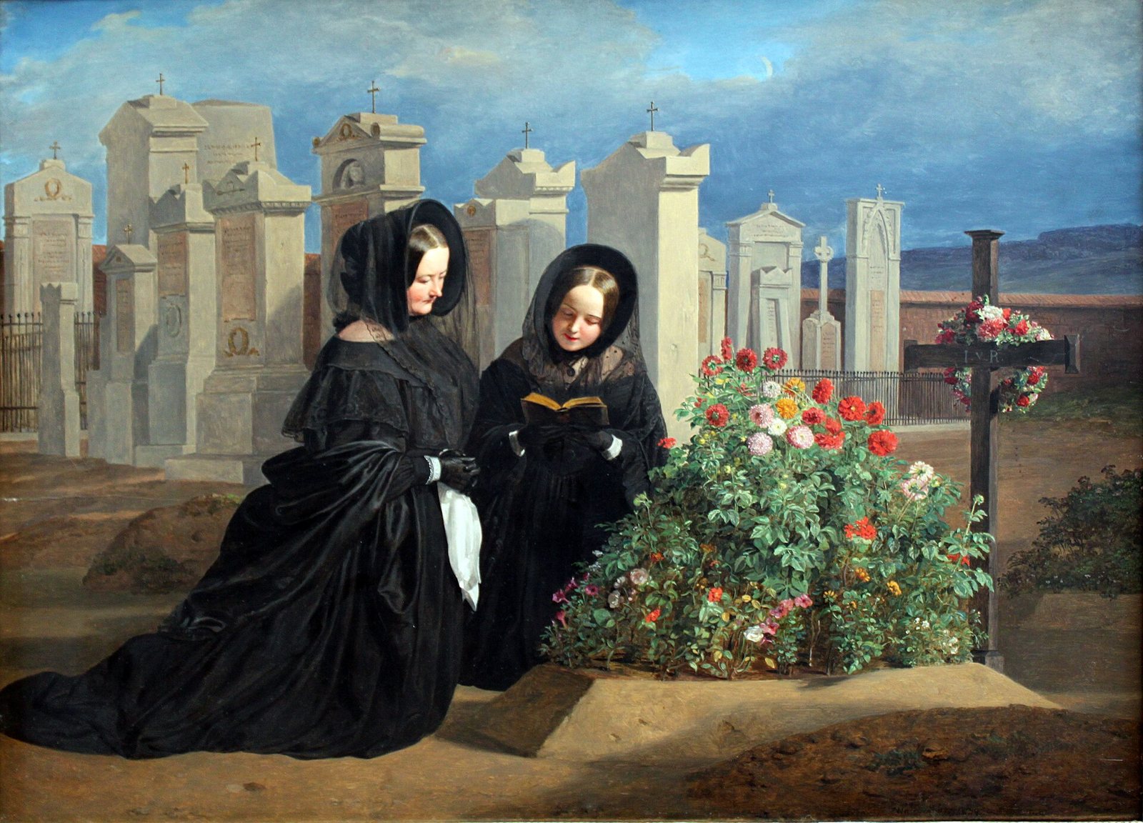 A woman and a girl in black mourning dress kneel at a grave heaped with red and pink flowers, the girl holding a prayer book, with rows of pale monuments and a wooden cross behind them