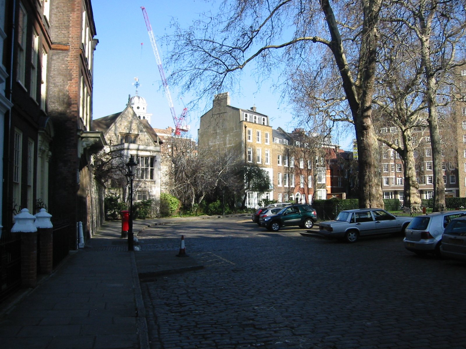 A quiet cobbled corner of Charterhouse Square in London, with bare trees, parked cars and old brick buildings on both sides