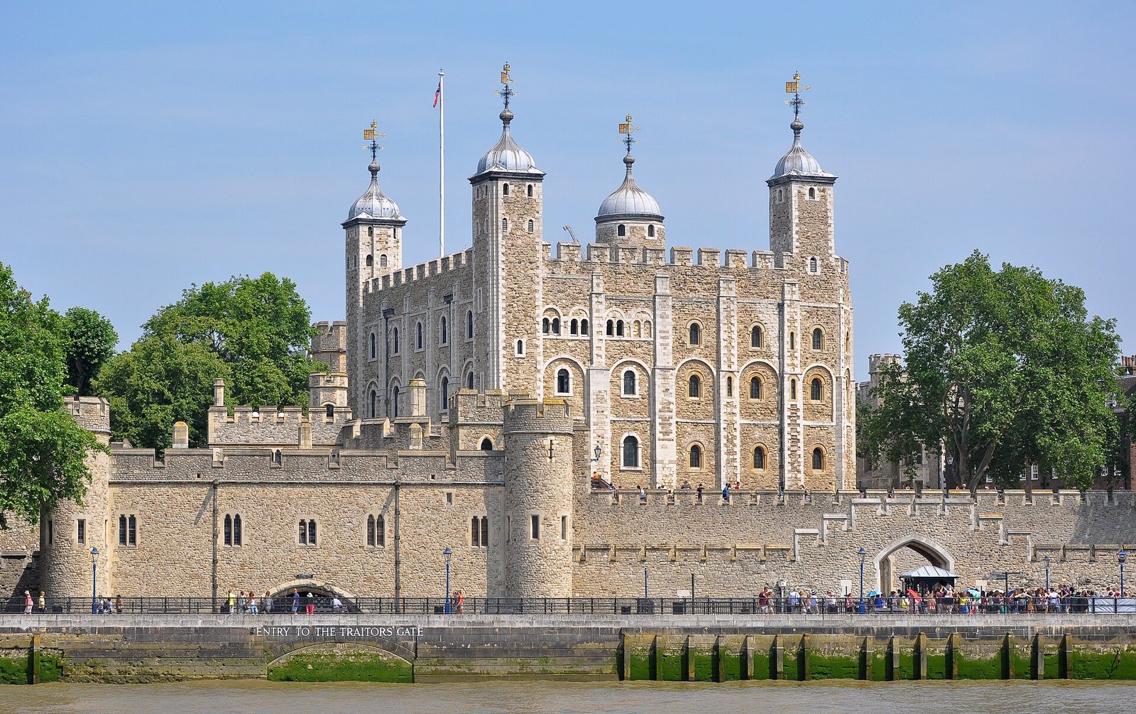 The White Tower and the walls of the Tower of London seen from the River Thames under a pale sky