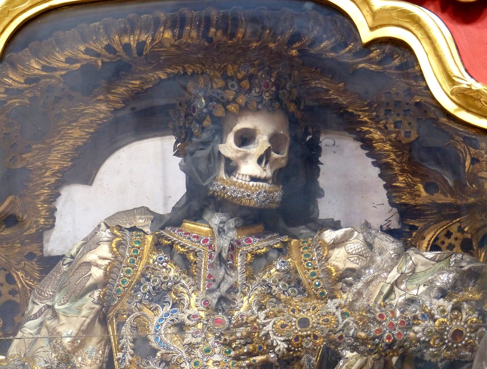 Close view of the catacomb saint Gratian at Waldsassen, the skull framed by a gilded crown and the body covered in gold embroidery, colored stones and pearls