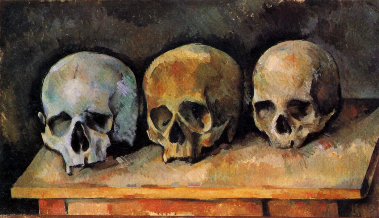 Cézanne's The Three Skulls: three skulls in a row on a wooden tabletop, one pale gray-blue and two yellow-ochre, against a dark brown wall