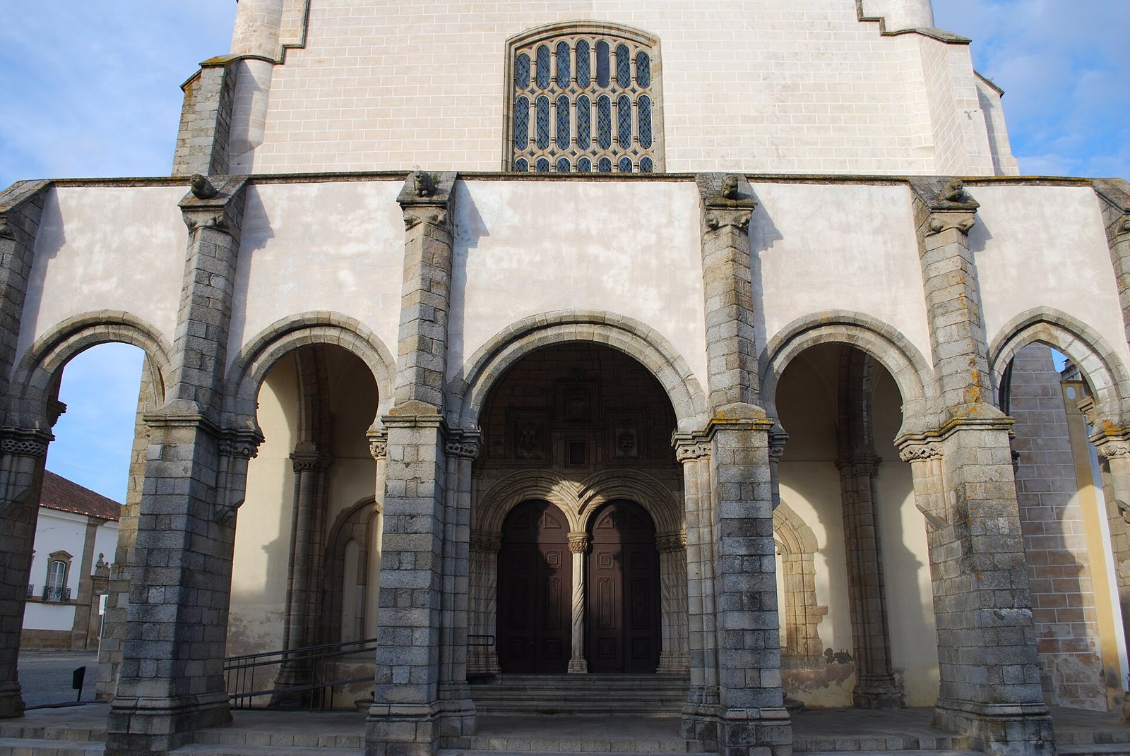 The front of the Igreja de São Francisco in Évora, a whitewashed facade above a porch of tall stone arches and buttresses