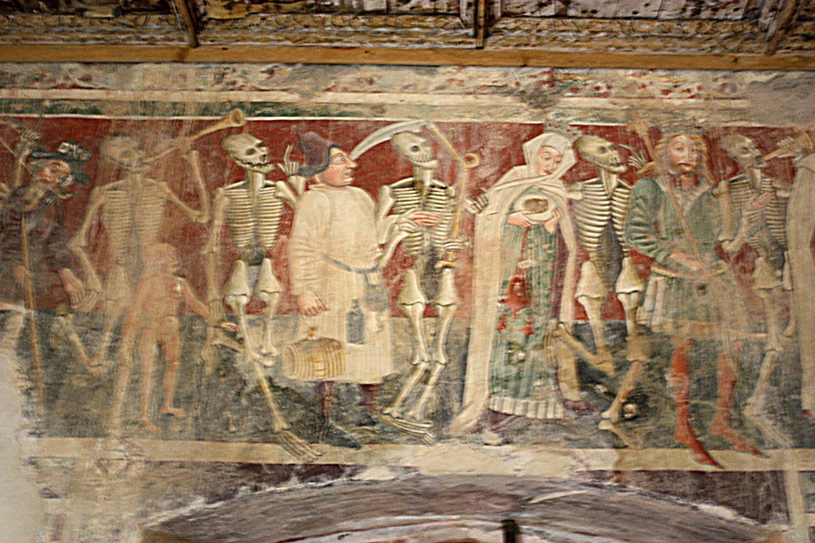 Fresco of grinning skeletons, one blowing a horn, each beside a living figure including a man in a white coat with a flask and a barrel, a woman in a white veil and a crowned man