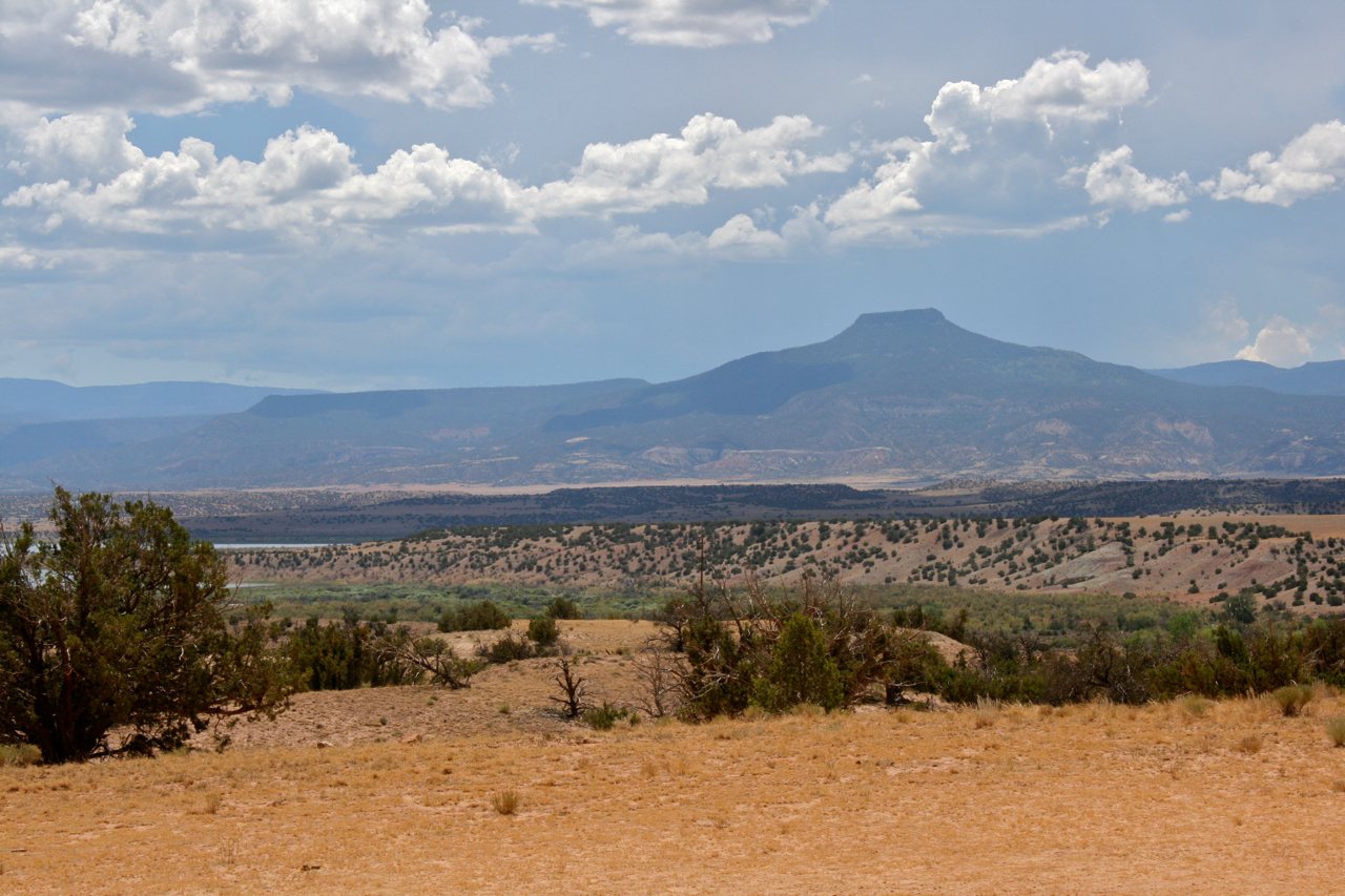 A flat-topped mountain on the horizon above dry golden hills and scrub, under a sky with scattered clouds