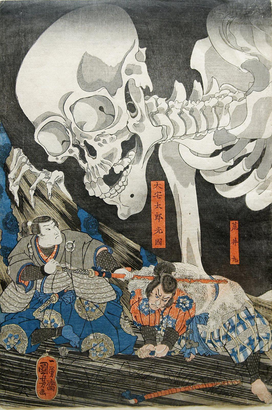 Center sheet of Kuniyoshi's print: a giant skeleton's skull and clawed hand loom out of the dark over two samurai crouched on the floorboards