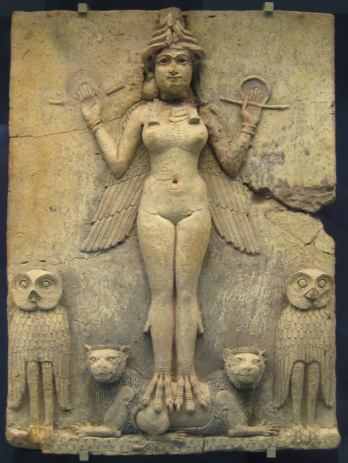 Relieve de arcilla de una diosa alada con tocado de cuernos, que sostiene una vara y un anillo en cada mano alzada, con pies de garras sobre dos leones y un gran búho a cada lado