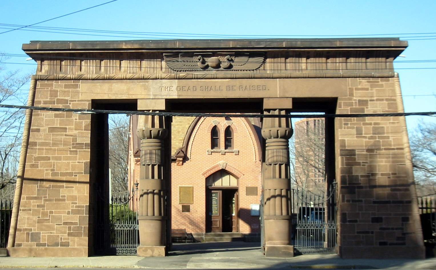 The brownstone Egyptian Revival gateway of Grove Street Cemetery, inscribed The Dead Shall Be Raised, with its lotus columns and winged sun disk