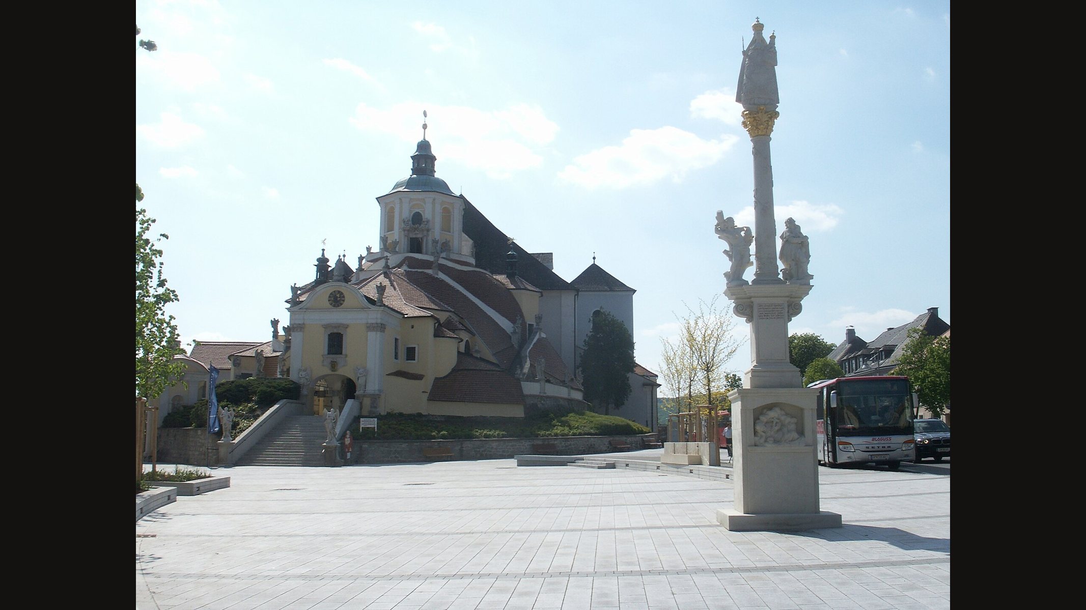 The Bergkirche in Eisenstadt, a domed baroque church at the end of a wide paved square, with a tall Marian column at the right