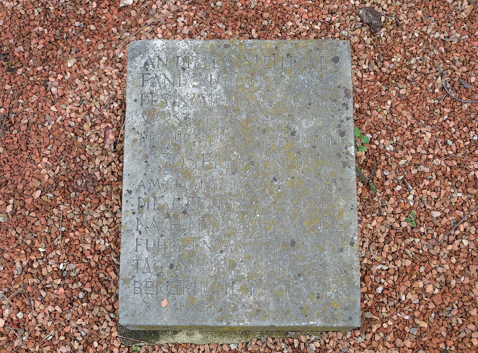 A weathered stone plaque with an inscription laid in red gravel in the Haydnpark, Vienna, marking the former grave of Haydn