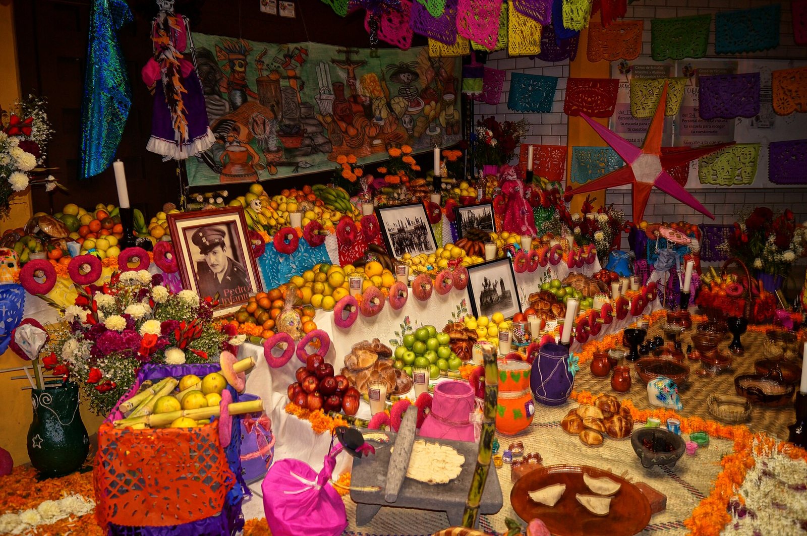 Una gran ofrenda tradicional en Mixquic cubierta de fruta, pan, flores, papel picado y fotografías enmarcadas de los difuntos, con pétalos de cempasúchil en el borde