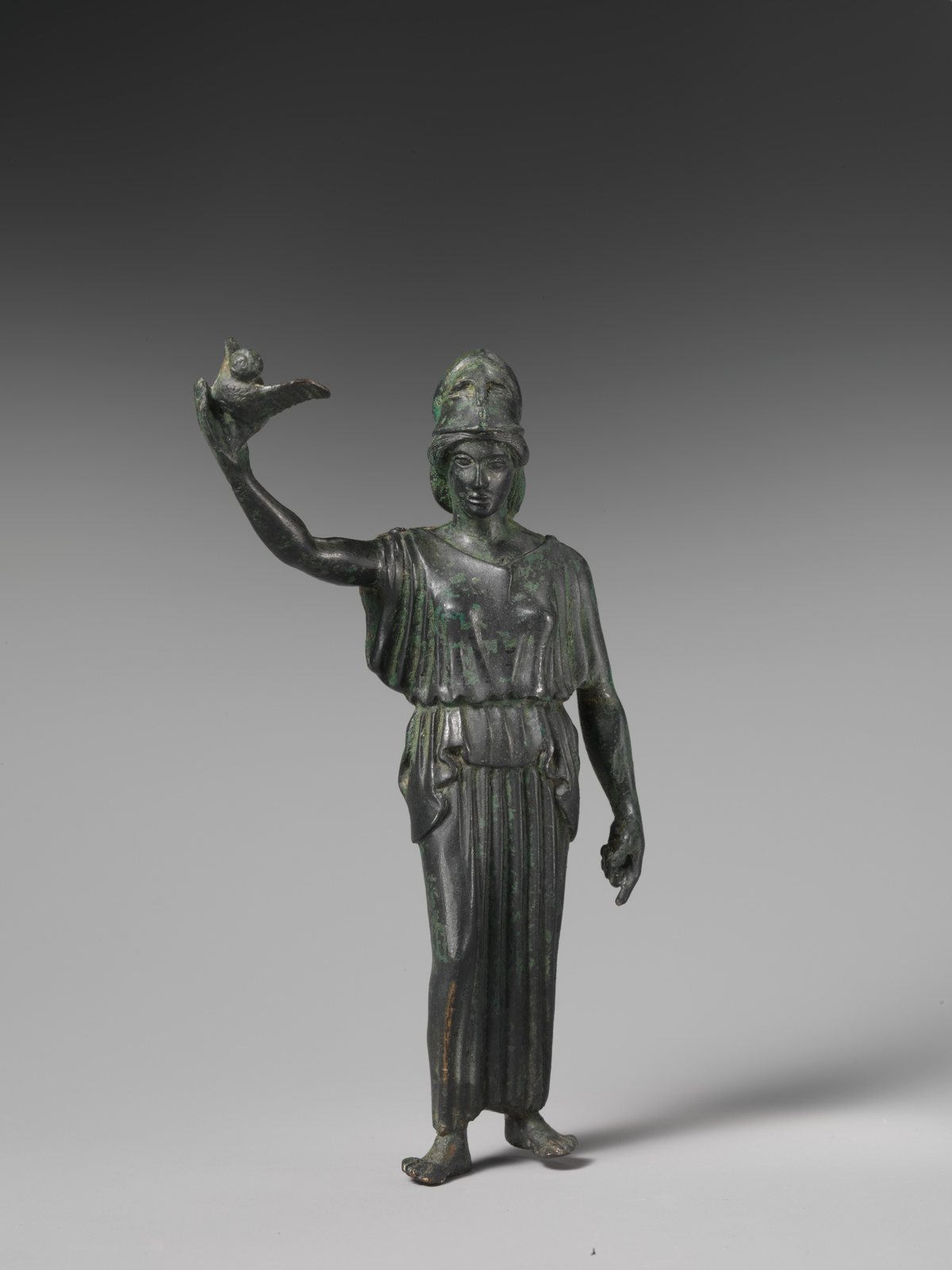 A bronze statuette of Athena in a crested helmet and long robe, holding up a small owl on her raised hand