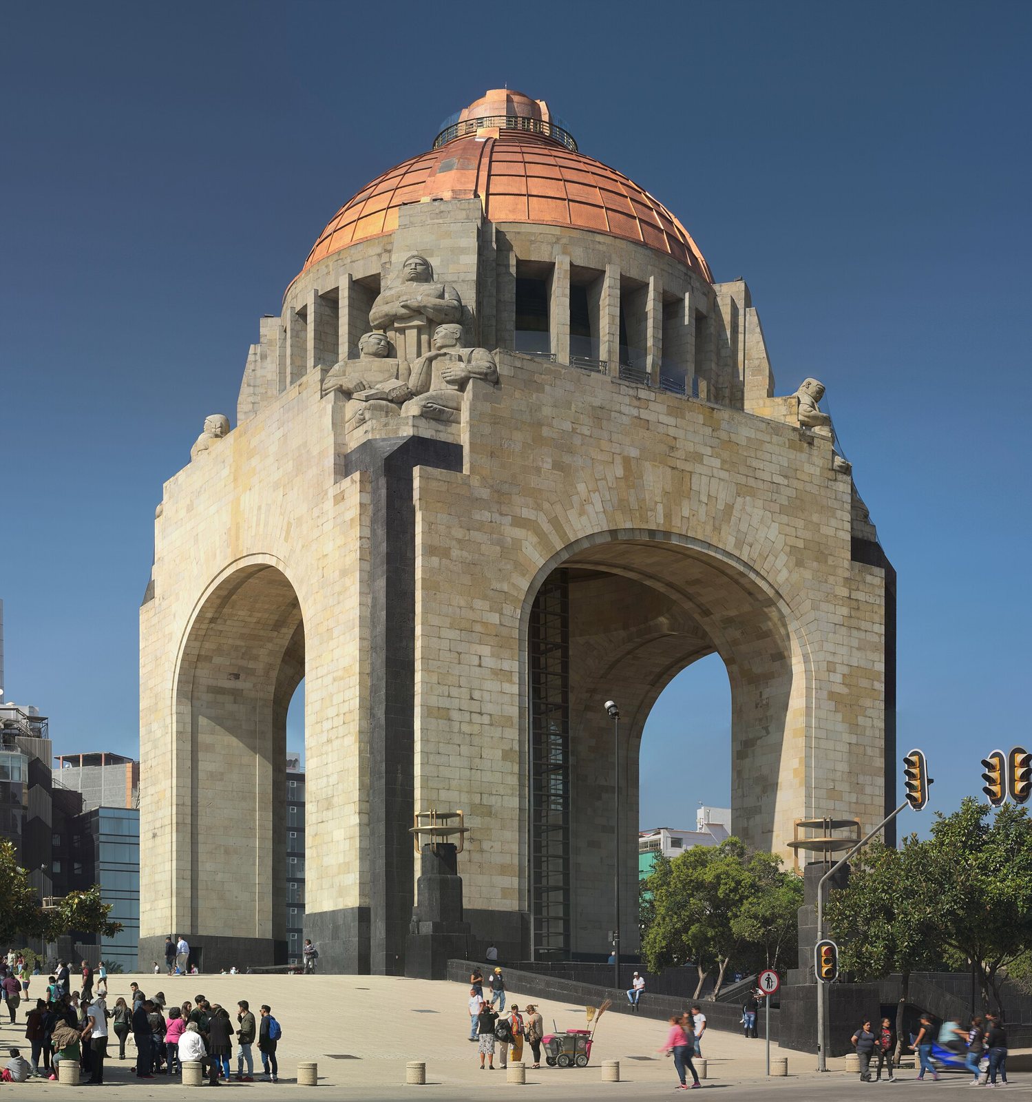 The Monumento a la Revolución in Mexico City, a large stone arch structure with a copper dome, seen from the plaza at its foot