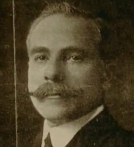 A sepia portrait photograph of the embalmer Alfredo Salafia, a man with a moustache and dark hair, wearing a dark suit