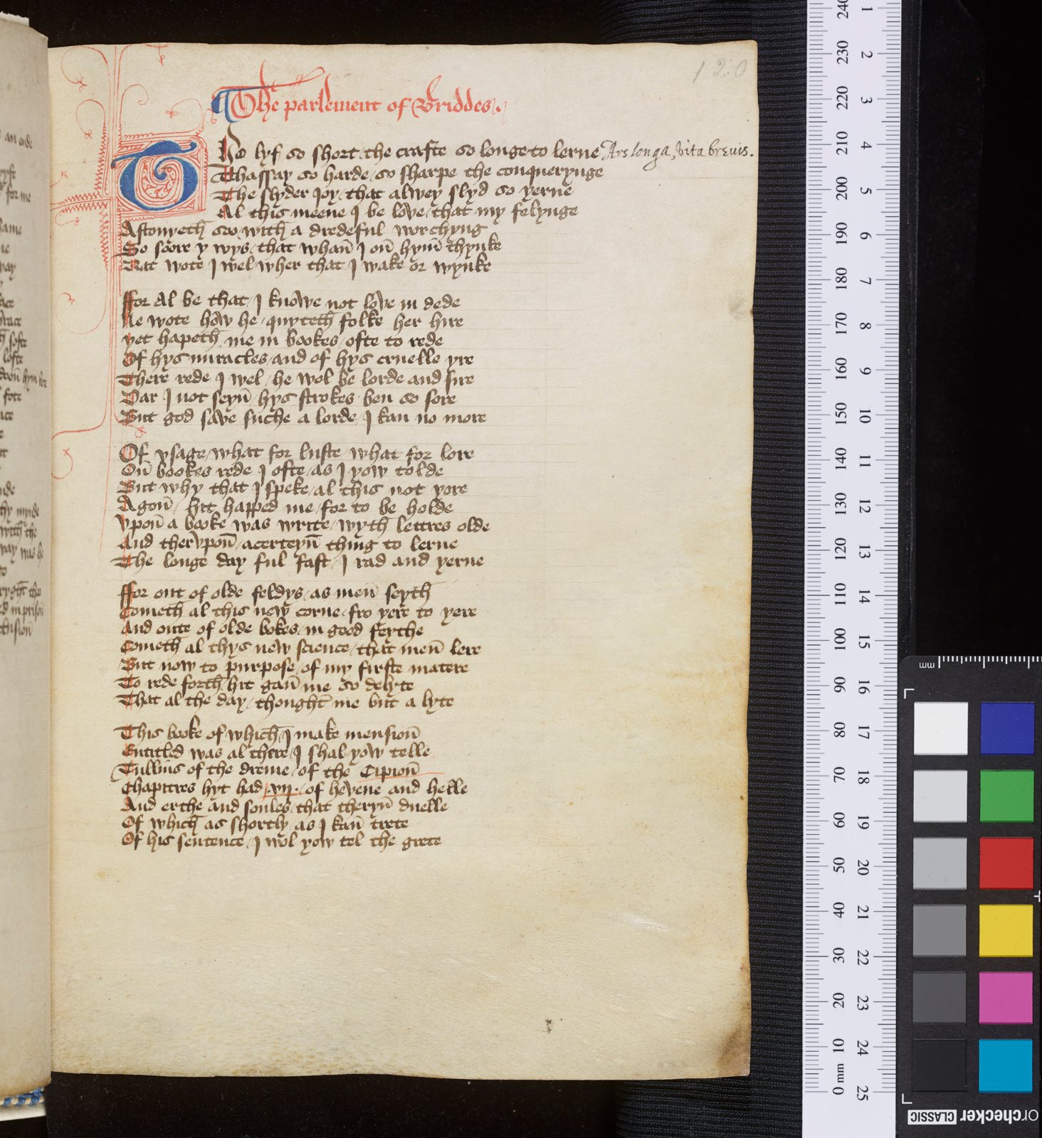 A manuscript page of handwritten Middle English verse in brown ink, headed in red and opening with a large decorated initial, photographed beside a ruler and a colour chart