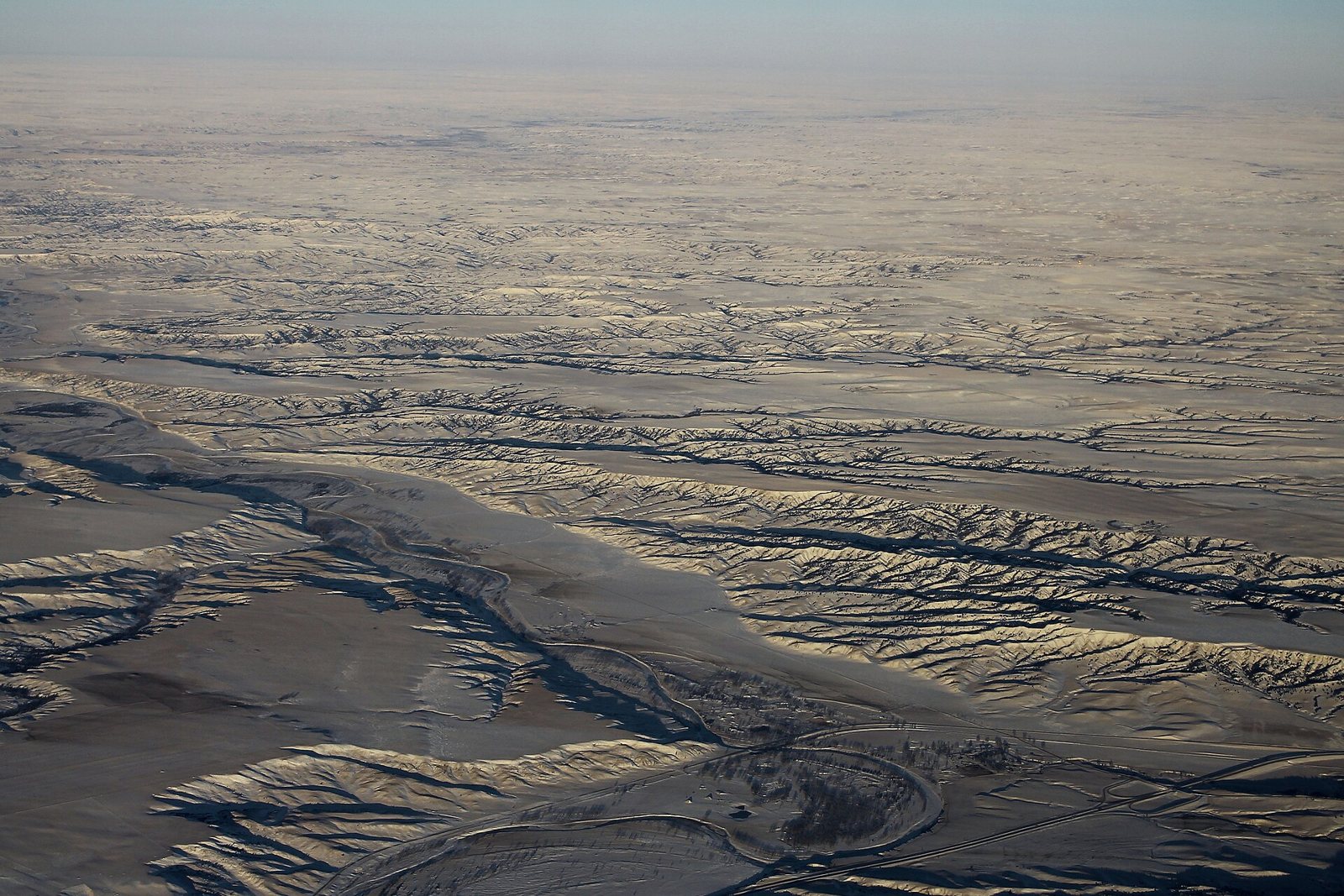 Aerial view of eroded badlands and river valleys under thin snow along the Cheyenne River in western South Dakota