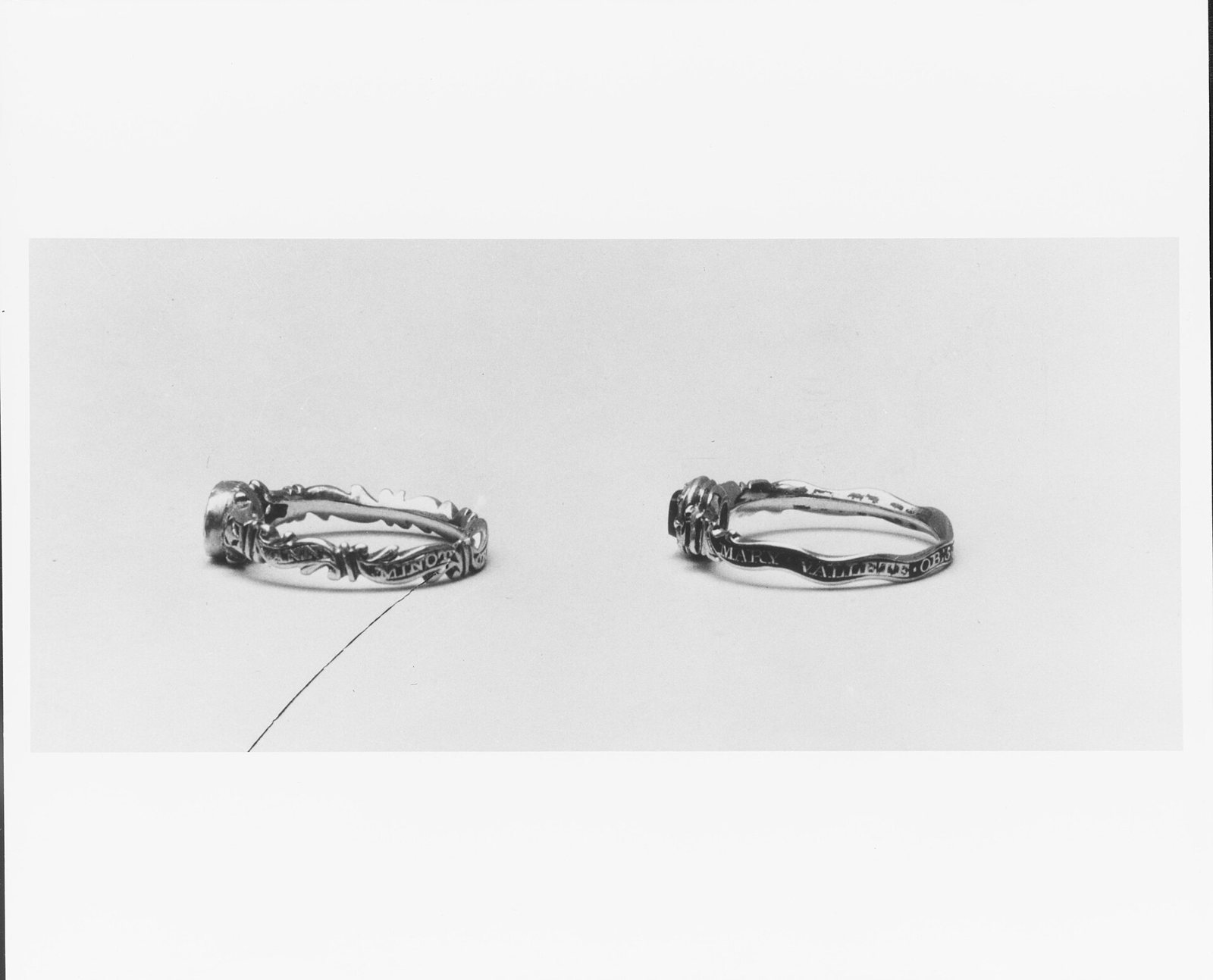 Two slim mourning rings photographed side by side on a pale ground