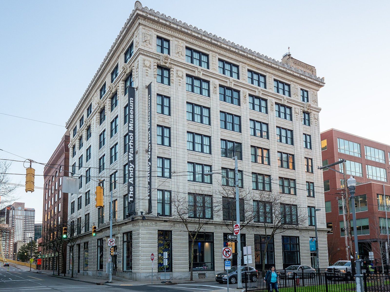 The Andy Warhol Museum in Pittsburgh: a pale stone building of about seven floors with tall rows of windows and a vertical sign down its corner, seen from the street